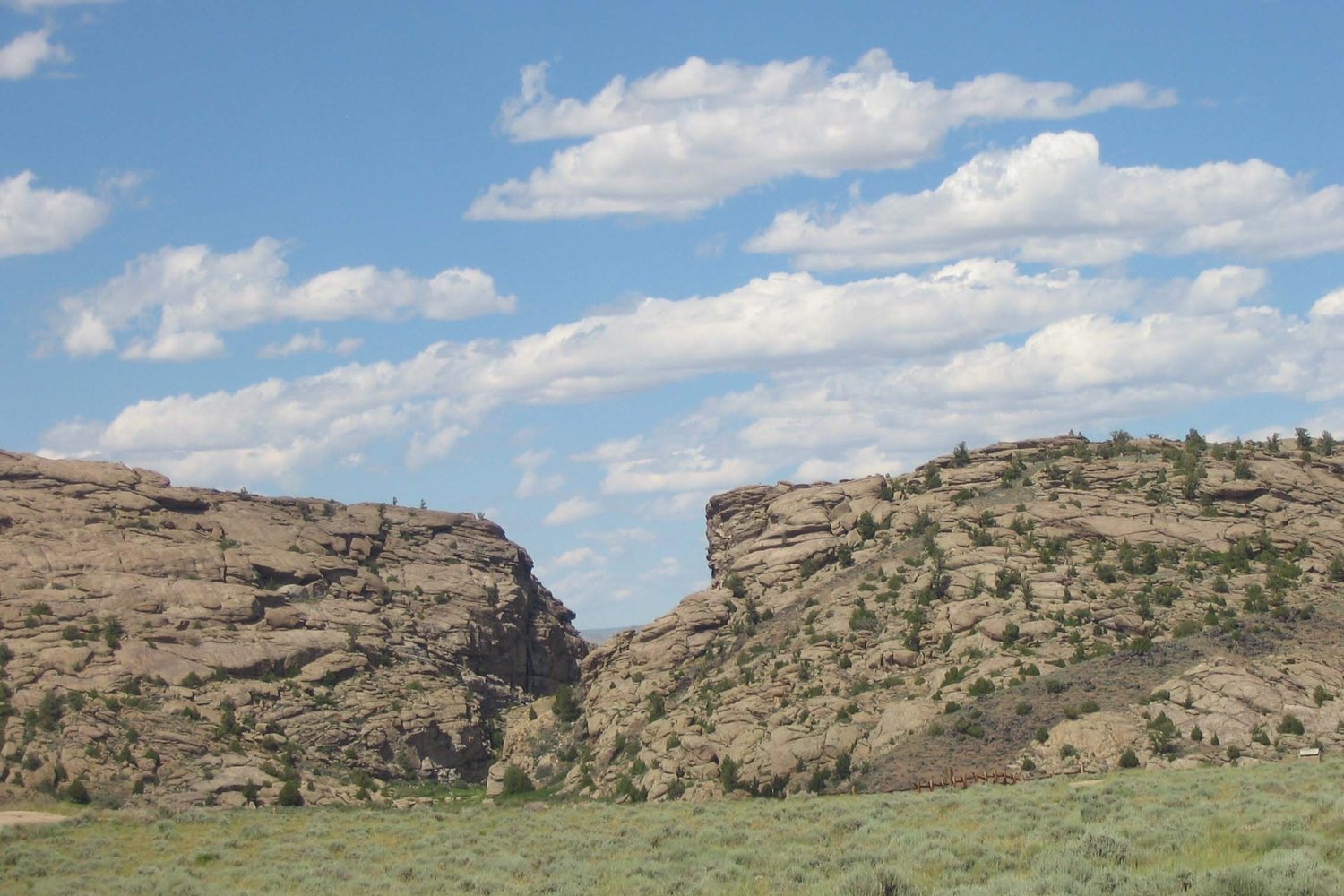 The narrow cleft of Devil's Gate cut through a granite ridge above a green sagebrush flat.