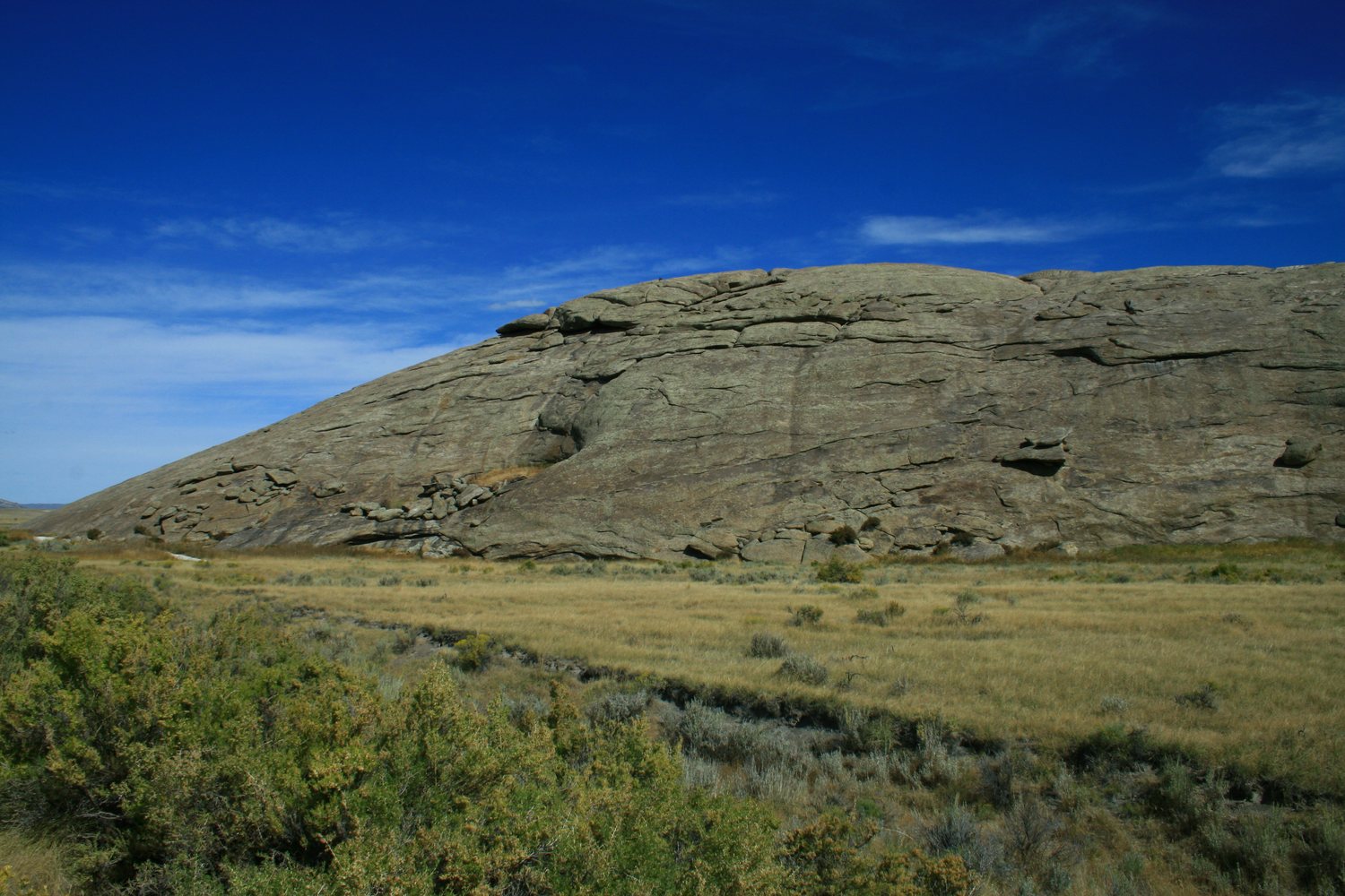 The long granite hump of Independence Rock above sagebrush under a deep blue sky.